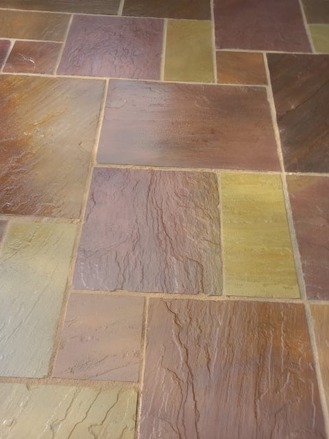 Close-up of multicolored stone tile flooring in earthy tones with varied surface textures and grout lines
