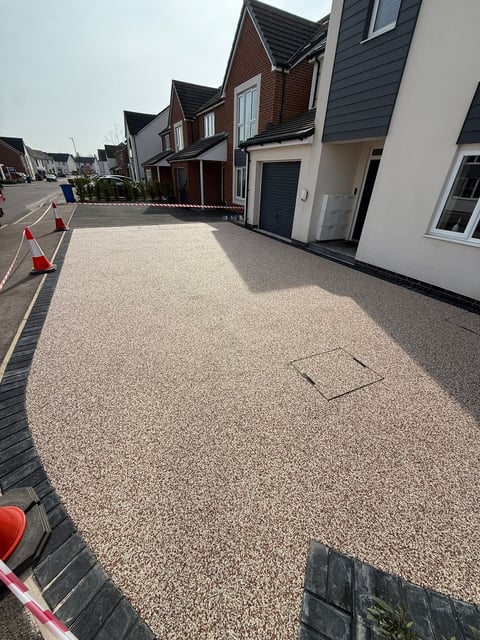 Newly paved gravel driveway in front of modern residential townhouses with black mansard roofs