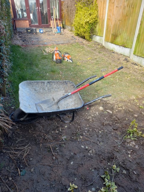 Wheelbarrow with spade in residential garden during landscaping or maintenance work