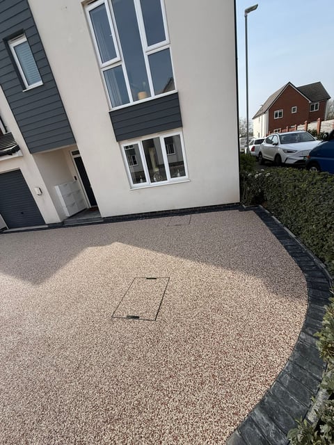 Modern white and dark blue-trimmed house with gravel driveway and access cover, parked white car visible, clear sunny day