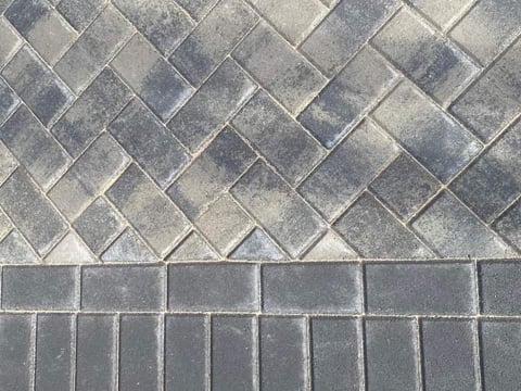 Two different paved surface patterns: herringbone brick layout above and rectangular tile pattern below