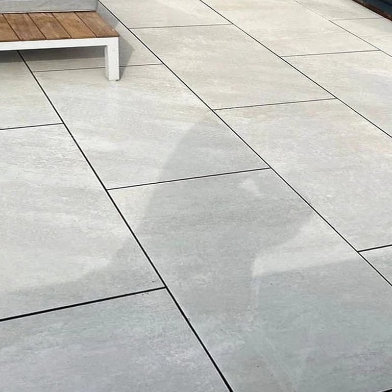 Modern polished concrete floor with large format tiles, accent wood flooring visible in background, and white trim detail